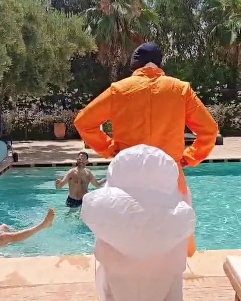 Le marié en combinaison orange avec des toilettes gonflables, au bord de la piscine de la villa